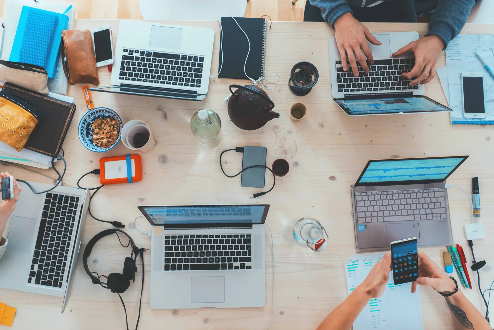 A shared worktable with notebooks and laptops